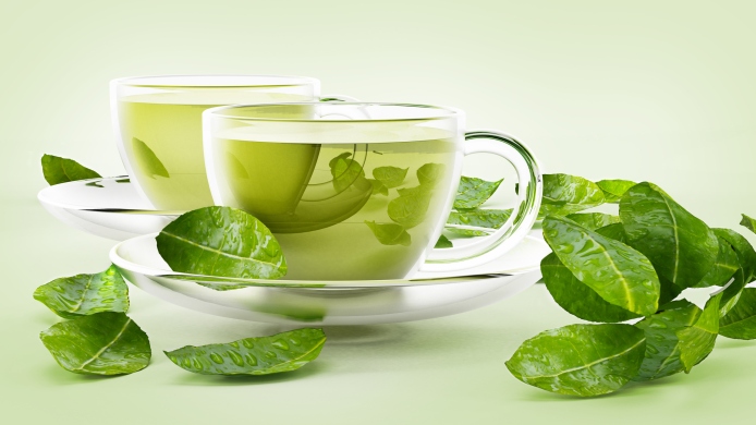 Glass cups with green tea and tea leaves isolated on white.